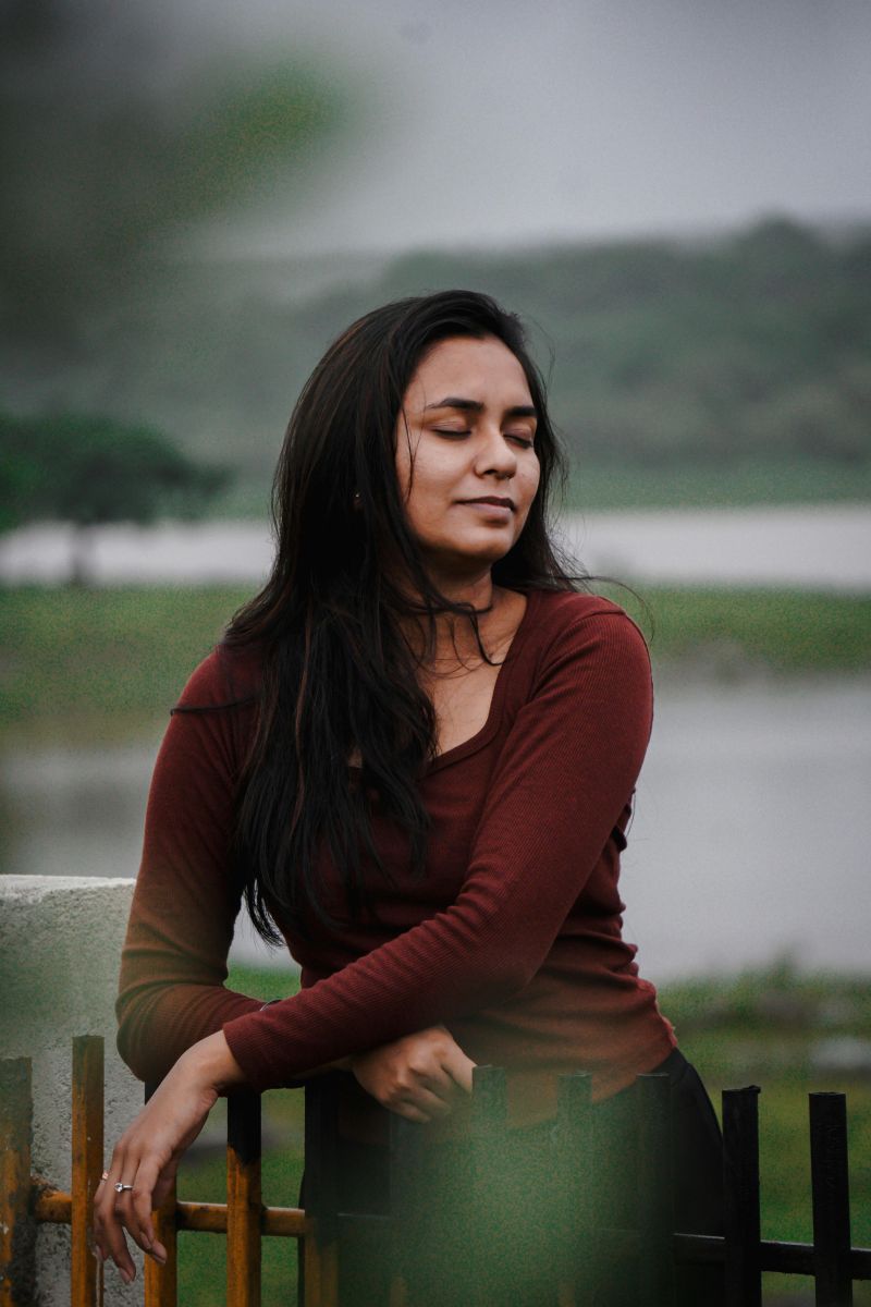 A serene portrait of a woman posing by a scenic lake, exuding elegance and calmness.